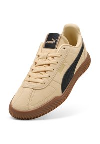 Puma tenisice s gornjim dijelom od smeđeg nubuka, crnim bočnim trakama i logotipom, prednjim vezanjem i smešastom gumenom potplatom.