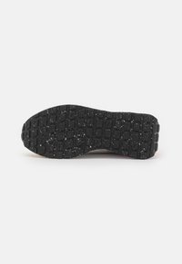 Semelle de chaussure en caoutchouc noir texturé avec un motif en grille, conçu pour l'adhérence et la durabilité. Contient des éclats blancs.