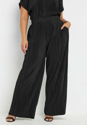 Pantalons noirs à jambes larges, plis marqués, avec une texture lisse et une taille élastique. Dotés de poches latérales et d'une coupe décontractée.