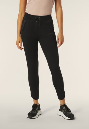 Pantaloni della tuta neri con un design aderente, vita elasticizzata, cordoncino e tasche laterali con un accento testurizzato sui lati.