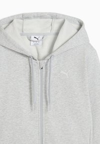 Ανοιχτό γκρι φούτερ με φερμουάρ, κατασκευασμένο από απαλό, υφασμάτινο ύφασμα με υφή. Διαθέτει τσέπη καγκουρό, κουκούλα με κορδόνι και λευκό λογότυπο στο στήθος.