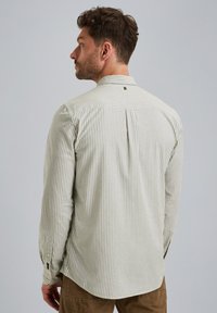 Camisa de manga larga a rayas en verde claro y blanco roto, con un cuello clásico, puños de botón y un detalle de pliegue en la espalda.