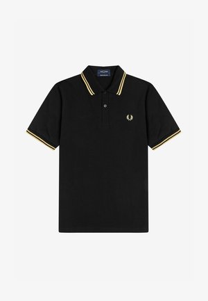 Polo negra con rayas amarillas en el cuello y las mangas, con un pequeño logo bordado en el lado izquierdo del pecho. Material de algodón.