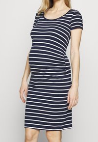Mörkblå och vitrandig gravidklänning med korta ärmar, figurnära design och sidokrusning för komfort. Mjuk, stretchig tyg.