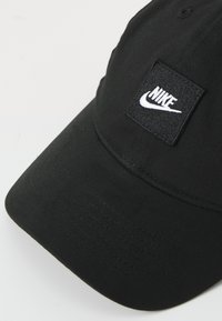 Boné preto de basebol feito de algodão. Apresenta um retângulo preto com o logotipo da Nike bordado em branco. Aba curvada e detalhes costurados.