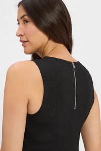 Robe noire sans manches en tissu texturé, présentant un motif subtil et une fermeture éclair argentée visible dans le dos.