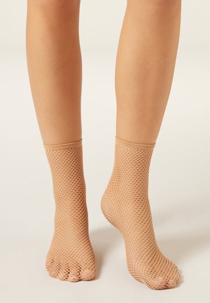 Nude ankelstrømper i netstof med åbne tæer, der har et struktureret mesh-mønster og elastiske manchetter for en sikker pasform.