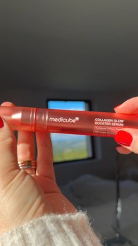 Czerwona przezroczysta butelka z serum z dozownikiem na pompkę. Etykieta zawiera napis „medicube COLLAGEN GLOW BOOSTER SERUM” oraz szczegóły produktu w białym tekście.