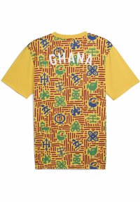 Kortærmet gul t-shirt med et flerfarvet mønster bestående af geometriske og organiske former; "GHANA" i hvide bogstaver på ryggen.