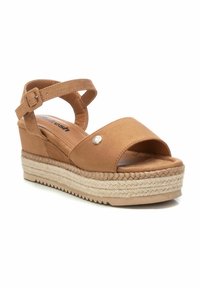 Sandalias de cuña marrón con una amplia correa frontal y correa para el tobillo ajustable. Presentan una plataforma envuelta en yute y un pequeño acento metálico.