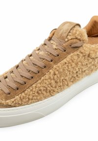 Sneaker beige con tomaia testurizzata e pelosa, con accenti in suede e lacci piatti beige. Suola in gomma bianca con grip testurizzato.