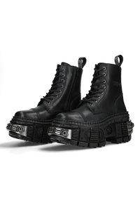 Black leather combat boots with chunky rubber soles, lace-up front, side zipper, and metallic accents on the sole design.