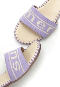 Infradito viola con cinturini in tessuto morbido, suole in pelle beige e dettagli di cucitura visibili. Accentuati da testo con logo sui cinturini.