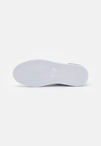 White sneaker sole with herringbone tread pattern, featuring a rectangular logo patch in the center. Material appears rubber with detailed texture.