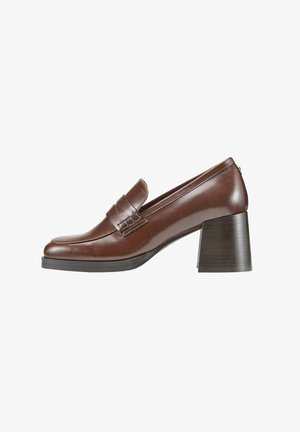 Mocassins à talons en cuir marron avec un bout rond, présentant un détail de sangle à l'avant, un talon carré et une texture lisse.