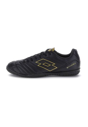Chaussure de football basse noire avec logo doré et texte "STADIO", design matelassé à l’avant-pied et fermeture à lacets, vue de côté.