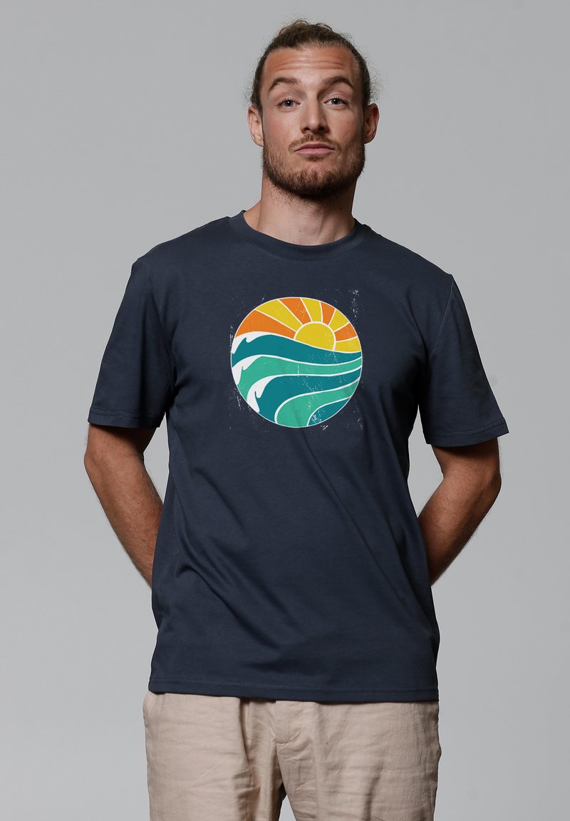 Marineblauwe T-shirt met korte mouwen met een ronde graphic van een zon en golven in oranje, groen en wit. Zachte katoenen stof.