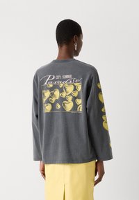 Gray long-sleeve shirt featuring a yellow heart pattern on the back, with text reading "CITY SUMMER Paradise" above the design.