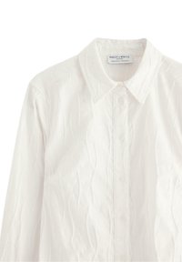 Hvid skjorte med knaplukning, lavet af et tekstureret væv, med en klassisk krave og fem matchende knapper foran.