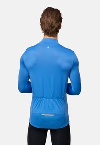 Sportieve longsleeve shirt in een levendige blauwe kleur, gemaakt van lichtgewicht, vochtafstotende stof; heeft een aansluitend ontwerp en een opening voor een achterzak.