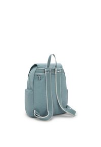 Zaino in tessuto color turchese con forma arrotondata, dotato di due spallacci regolabili, una maniglia superiore e tasche laterali. Accentuato da una leggera cucitura.
