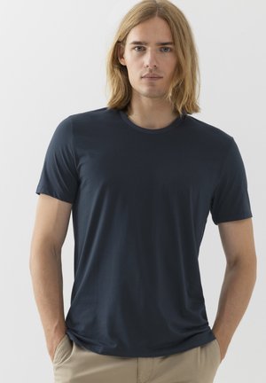 T-shirt blu navy a maniche corte in tessuto morbido, con scollatura rotonda e vestibilità rilassata, abbinato a pantaloni chiari.