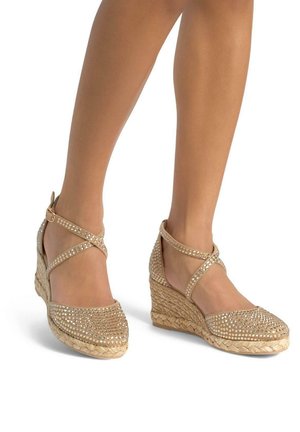 Beige wedge espadrilles with crisscross straps, embellished with clear rhinestones on the upper, featuring a natural woven jute sole.