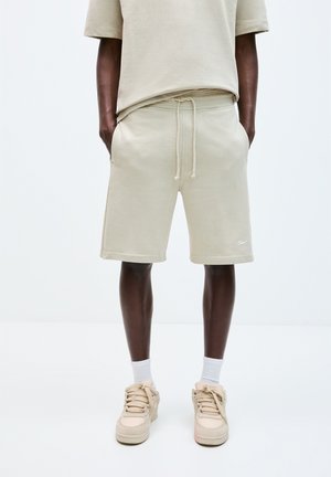 Beige bavlněné šortky s elastickým pasem a šňůrkou, se bočními kapsami a malým logem na lemu. Design v casual střihu.