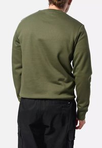 Sudadera de cuello redondo en verde oliva con puños acanalados, textura suave, vista trasera que muestra un diseño simple y un corte relajado, combinada con pantalones negros.