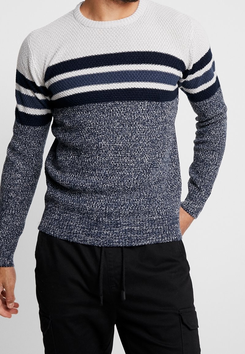 Navy and white striped knit sweater with textured pattern, round neckline, and ribbed cuffs. Body features a speckled navy design.
