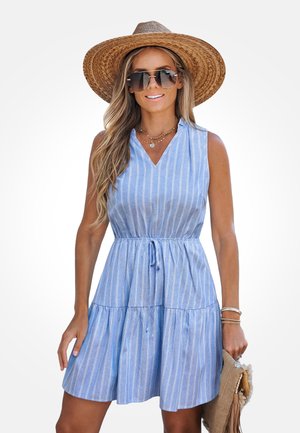 Niebieska sukienka bez rękawów z pionowymi białymi paskami, z dekoltem w serek, w talii marszczona, z falbanami i ściągaczem. Dopasowana do szerokiego kapelusza słomkowego.