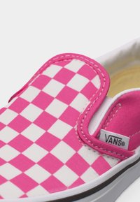 Różowo-biały slip-on Vans w kratkę z widoczną metką z logo i białą gumową podeszwą, widok z bliska.