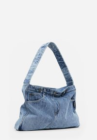 Denim-Schultertasche mit einer weichen, strukturierten Form. Aus blauem Denimstoff gefertigt, mit auffälligen Nähten und einem breiten Riemen, der Jeans ähnelt.
