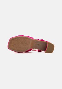 Roze hoge hak met een gestructureerde zool, bovenwerk van zacht materiaal en een smal bandjes ontwerp. Een natuurlijke rubberen buitenzool met een bloemmotief.