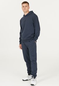 Mörkblå hoodie och sweatpants-set made of mjukt tyg, med en klassisk design med ribbade muddar och en subtil logotyp på bröstet.