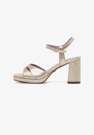 Sandalia metálica dorada con tacón de bloque, correa en el tobillo con hebilla, patrón texturizado de serpiente y forro interior púrpura.