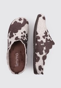 Zuecos de lana en diseño de manchas de vaca en crema y marrón, con una parte superior suave y texturizada y una forma redondeada. Cuenta con una suela oscura y una plantilla acolchada.