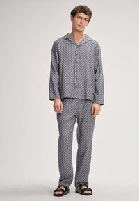 Gray patterned pajama set featuring a button-up long-sleeve top and matching pants, made of smooth fabric with a relaxed fit.