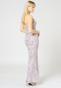Abito da sera lavanda con intricati motivi floreali in perline. Silhouette aderente, scollatura a halter, tessuto trasparente e fondo leggermente svasato. Tacchi argento.