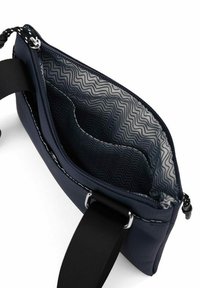 Námořnická látková taška se zipovým uzávěrem, s texturovaným interiérem se vzorem cikcak a pevným černým popruhem.