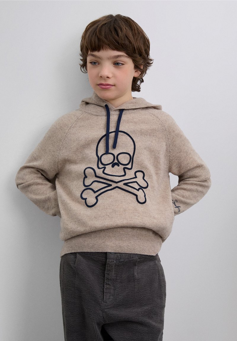 Beiger Hoodie aus weichem Stoff mit blauem Totenkopf- und Knochen-Design. Verfügt über eine Kängurutasche und kontrastierende blaue Kordeln.