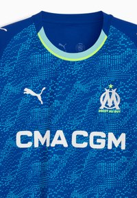 Blå sports trøje med et pixeliseret design, der har rund halsudskæring, Puma-logo og "CMA CGM"-tekst i hvid samt klubemblem.
