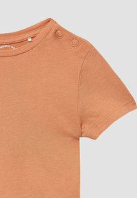 Kurze Ärmel orange T-Shirt aus weichem Stoff, mit zwei Druckknöpfen an der Schulter und einem runden Ausschnitt.