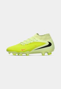 Bota de fútbol Nike de color amarillo brillante con cuello alto, parte superior texturizada, logotipos de swoosh en negro y rosa, y tacos moldeados sobre un fondo blanco.