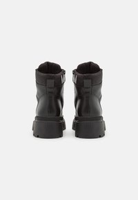 Bottines en cuir noir avec un col en tissu texturé, une semelle en caoutchouc épaisse et des zips sur les côtés pour un enfilage facile. Fini lisse avec des accents minimaux.