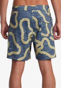 Herrbadshorts i marinblått med ett blommönster av gula blommor och detaljer av en karta. Har en bakficka och en texturerad tyg.