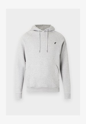 Felpa grigia a coste con coulisse regolabili, tasche laterali e piccolo logo nero sul petto. Tessuto morbido e strutturato.