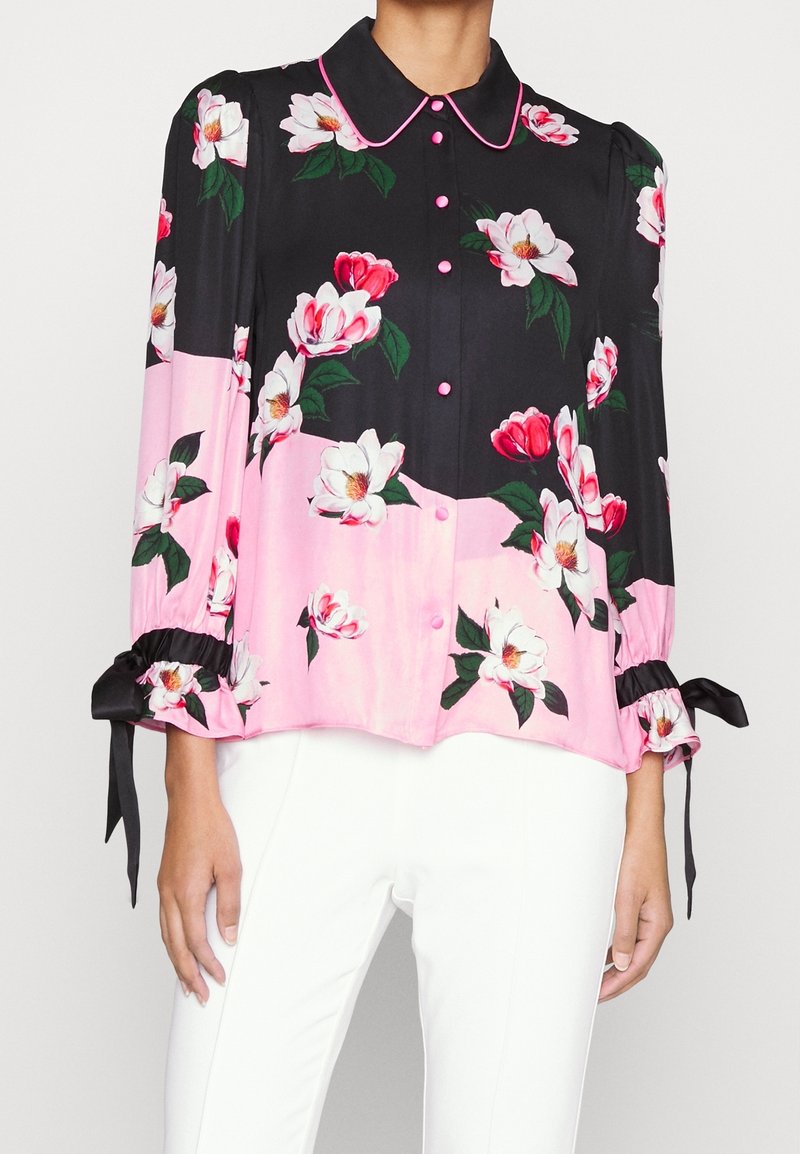 Blusa a bottone floreale con sfondo nero, dettagli rosa, tessuto lucido, colletto e maniche arricciate con legacci in raso nero.