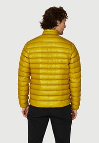 Gul, puffy jakke med høj krave, der har et vandret quiltet mønster, skinnende tekstur og tætsiddende pasform. Letvægts- og isoleret design.