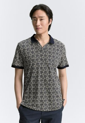 Camiseta polo azul marino con patrón circular en color blanco roto, de manga corta y un cuello oscuro en contraste. Fabricada con un tejido transpirable.